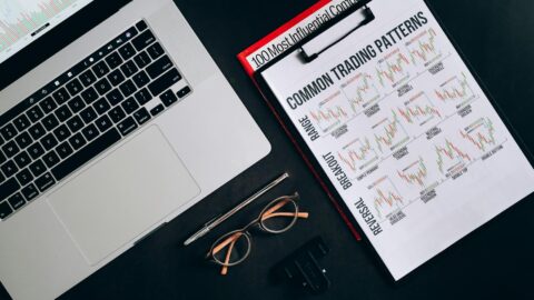 printout graphs on a clipboard beside a laptop